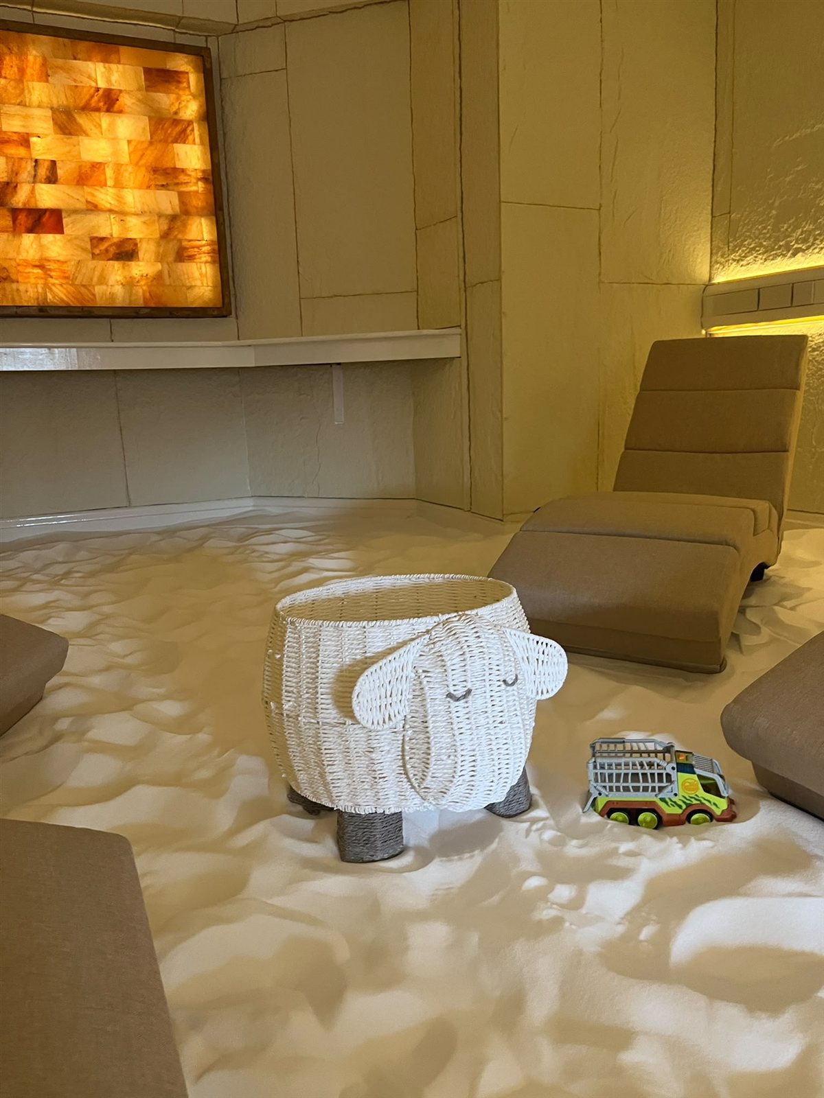 The children's salt play area at Pure Salt Therapy, with a wicker sheep basket and toys on the white salt floor